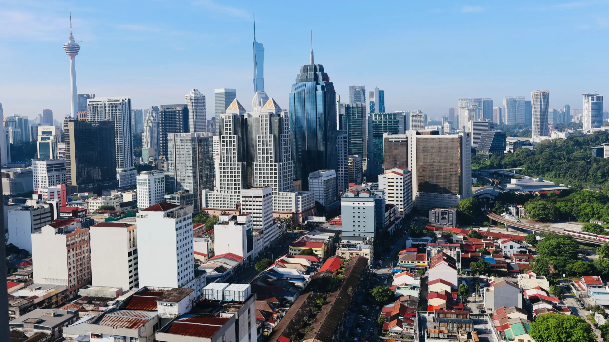 Daytime view of Kuala Lumpur, featuring a skyline of modern buildings and bustling urban development. 