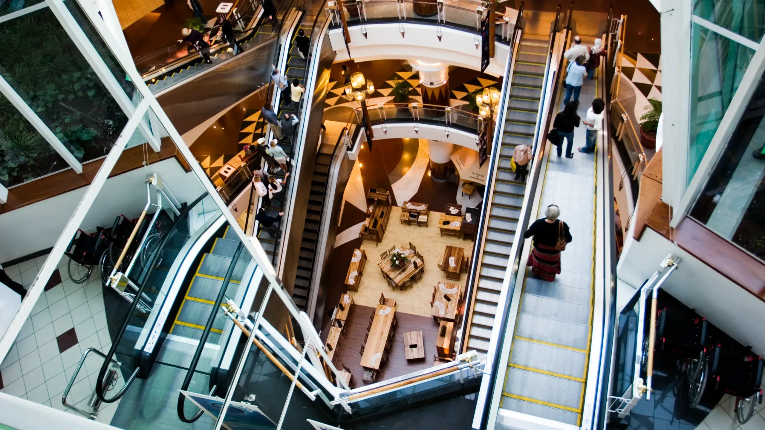 Overhead view of a shopping mall interior, showing retail spaces, walkways, and open communal areas. 