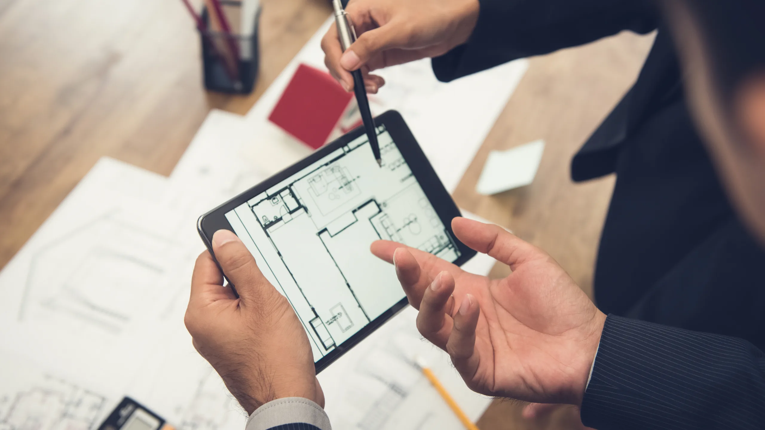 Real estate agent using a tablet to review a housing model during a property development consultation.