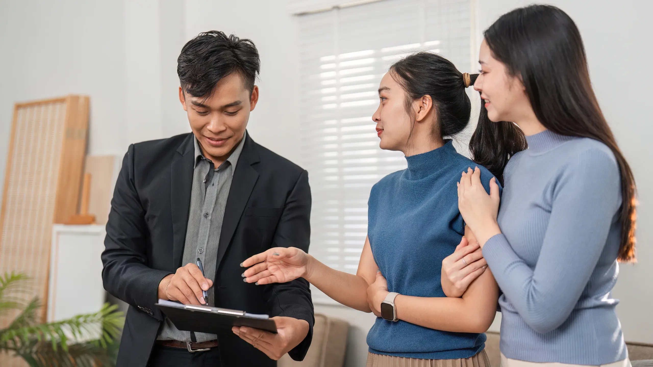 real estate agent showing two women details of a property