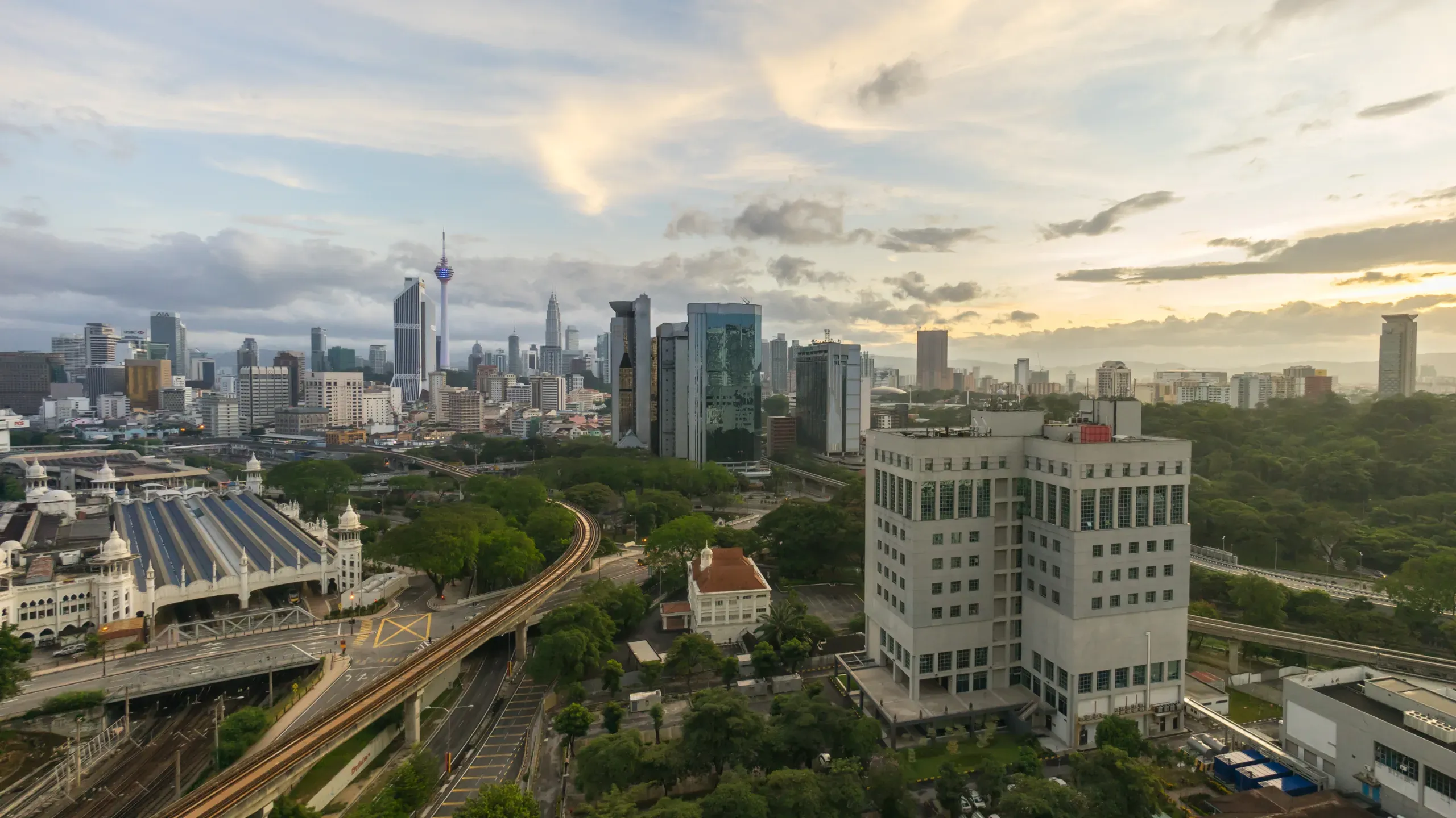 Sunrise over Kuala Lumpur, with the city skyline illuminated by soft morning light and a colourful dawn sky. 