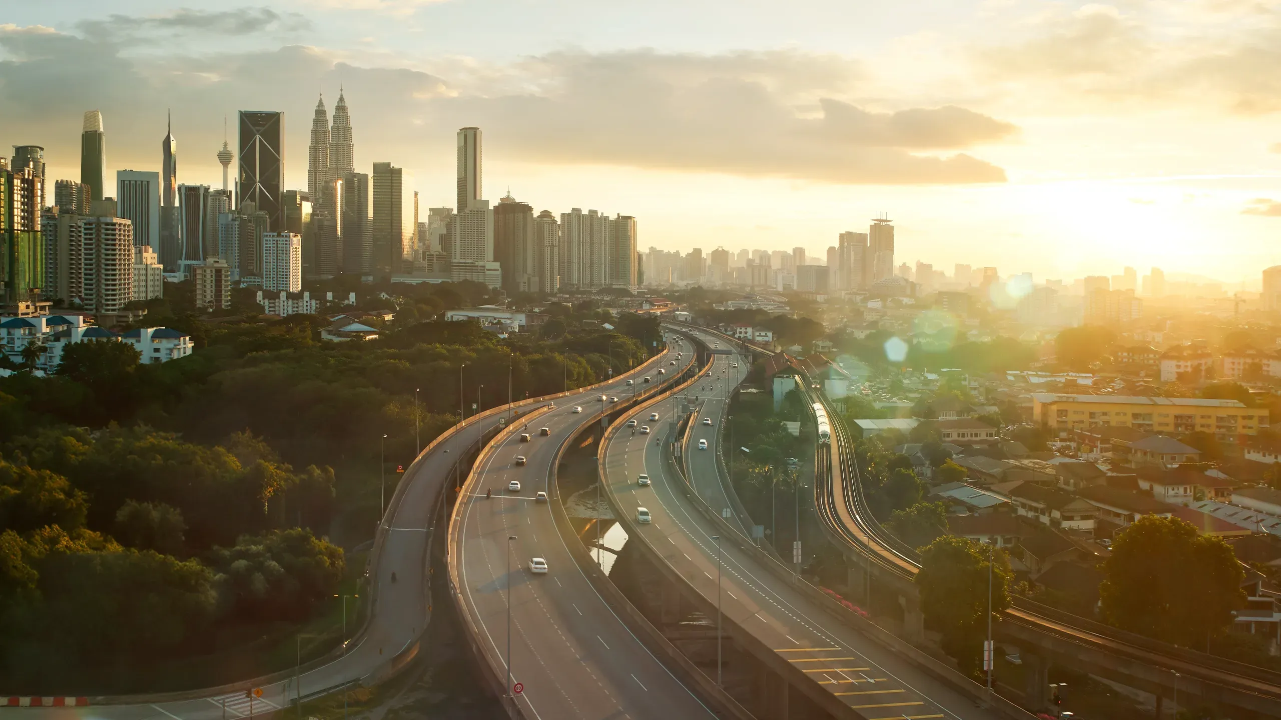 Sunset over Kuala Lumpur, with the city skyline silhouetted against a warm, colourful evening sky. 