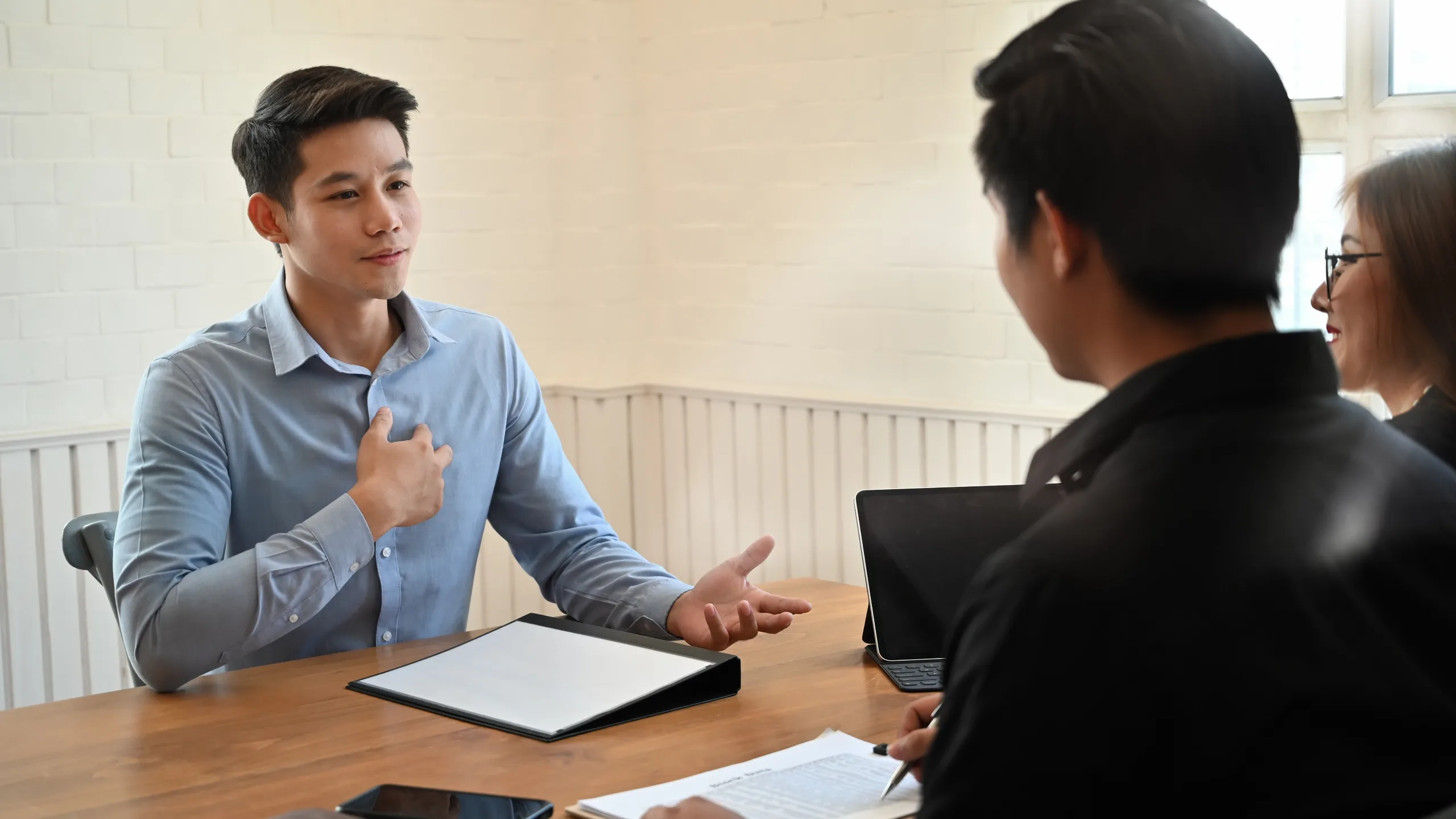 Young man talking with coworkers in a modern office collaborating and sharing ideas in a professional workplac