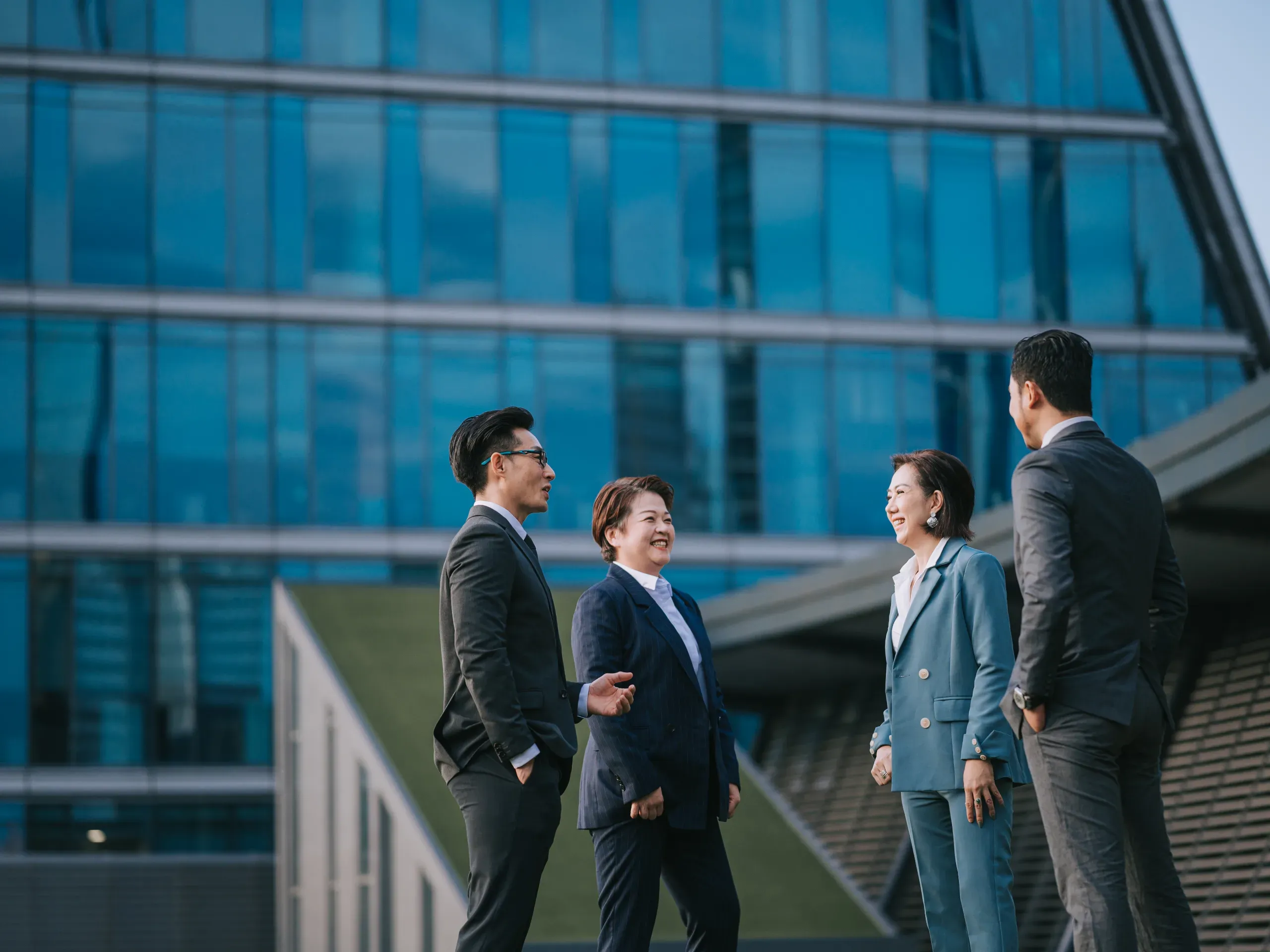 Business professionals meeting outside an office building, engaged in discussion within a corporate setting. 