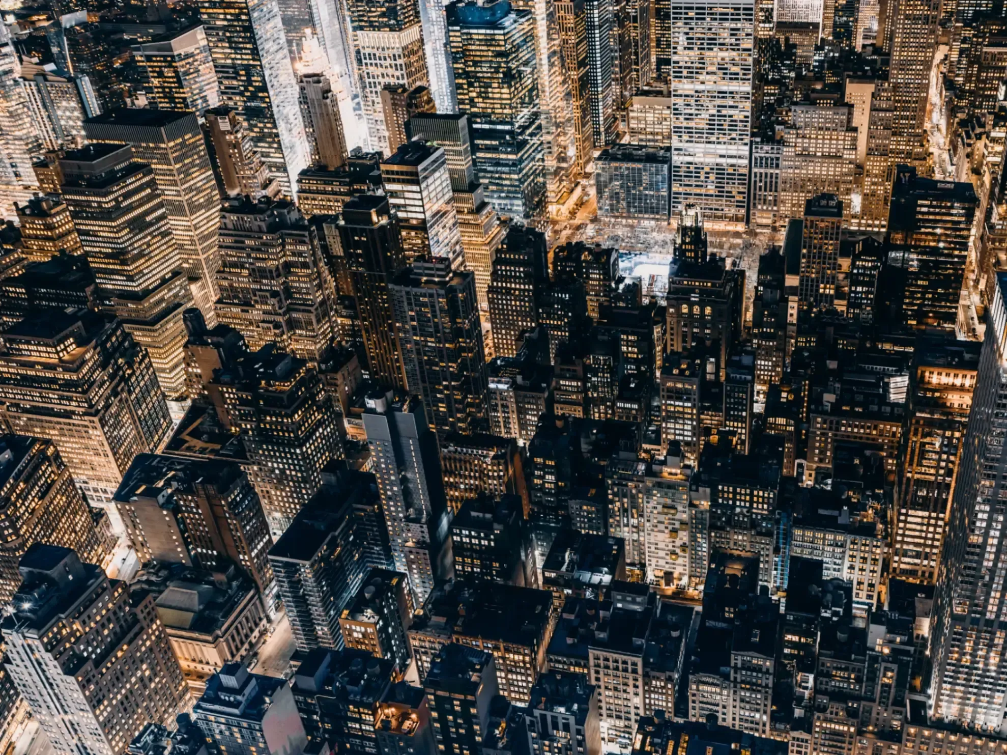Aerial view of a city at night, with illuminated buildings, streets, and traffic creating a vibrant urban scene. 