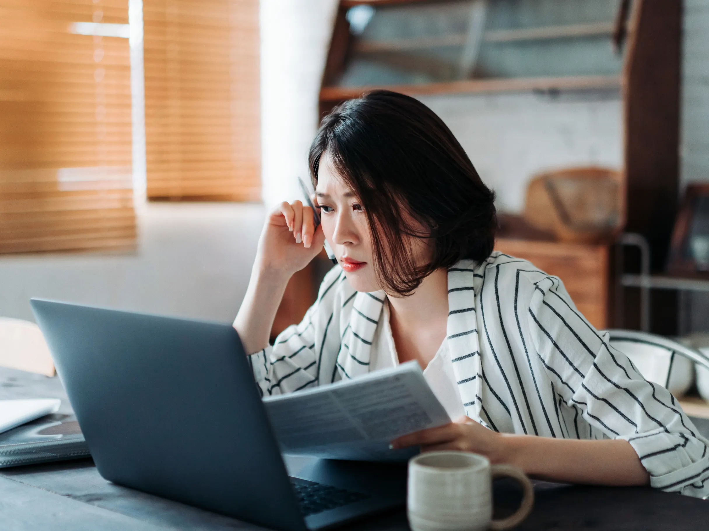 Asian businesswoman working at a desk in a modern office, focused on professional tasks and business activities.