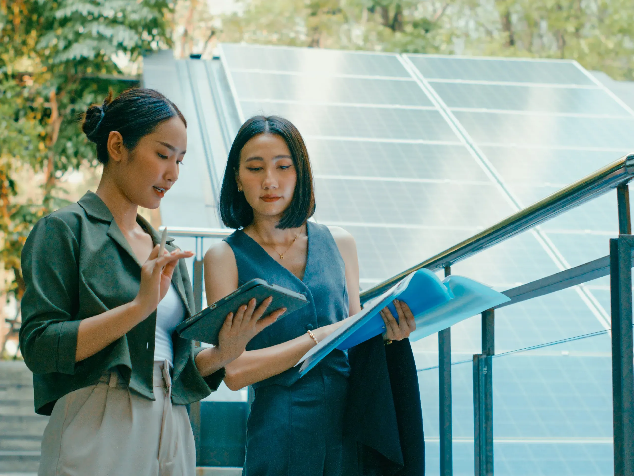 Asian businesswomen collaborating on a sustainable energy project in an urban environment, discussing plans and development initiatives. 