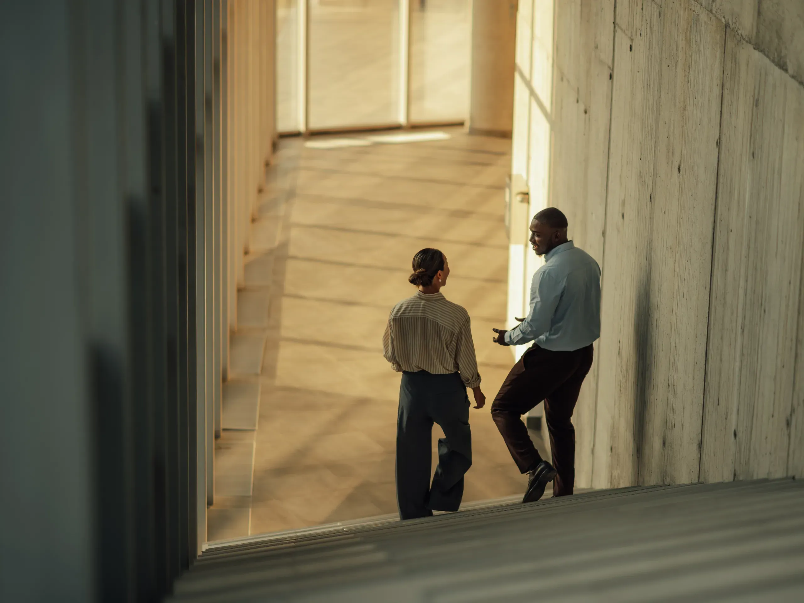 Businesspeople on a staircase in a modern office building, moving through a contemporary workplace environment. 