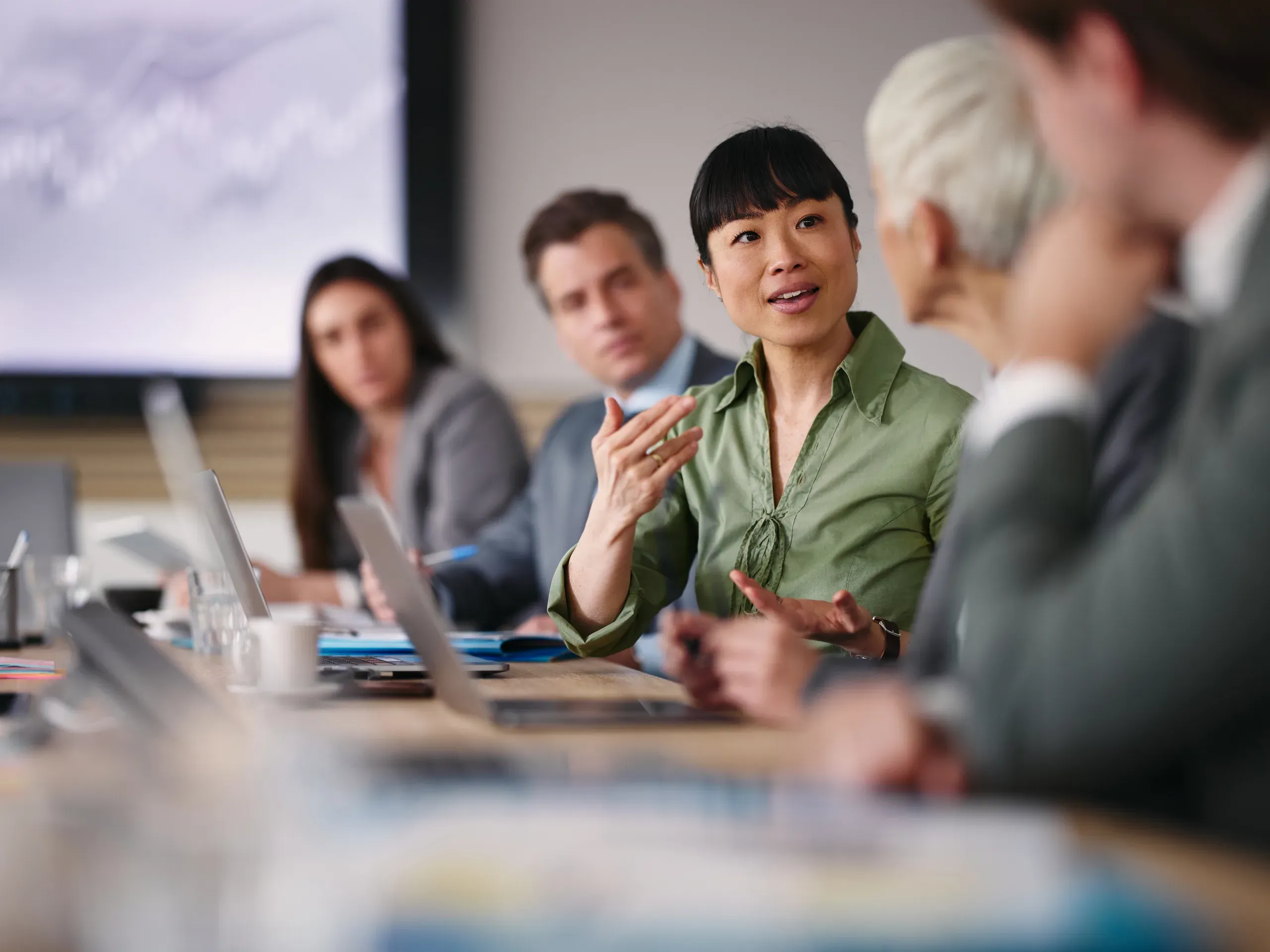 Businesswoman talking to her colleague during a meeting, engaged in discussion within a professional office setting. 