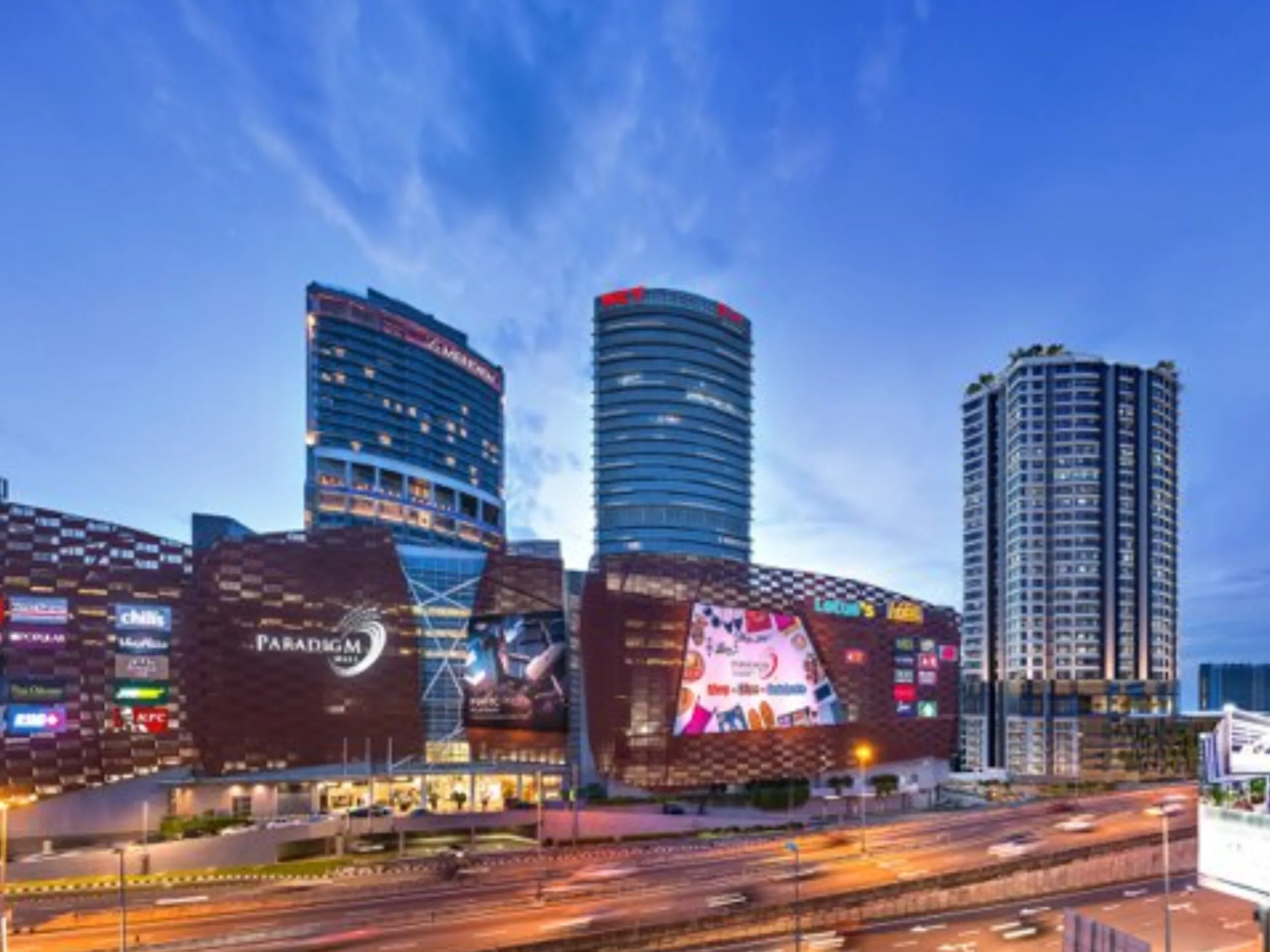 Busy city at night with illuminated buildings, vibrant streets, and streams of traffic lights.