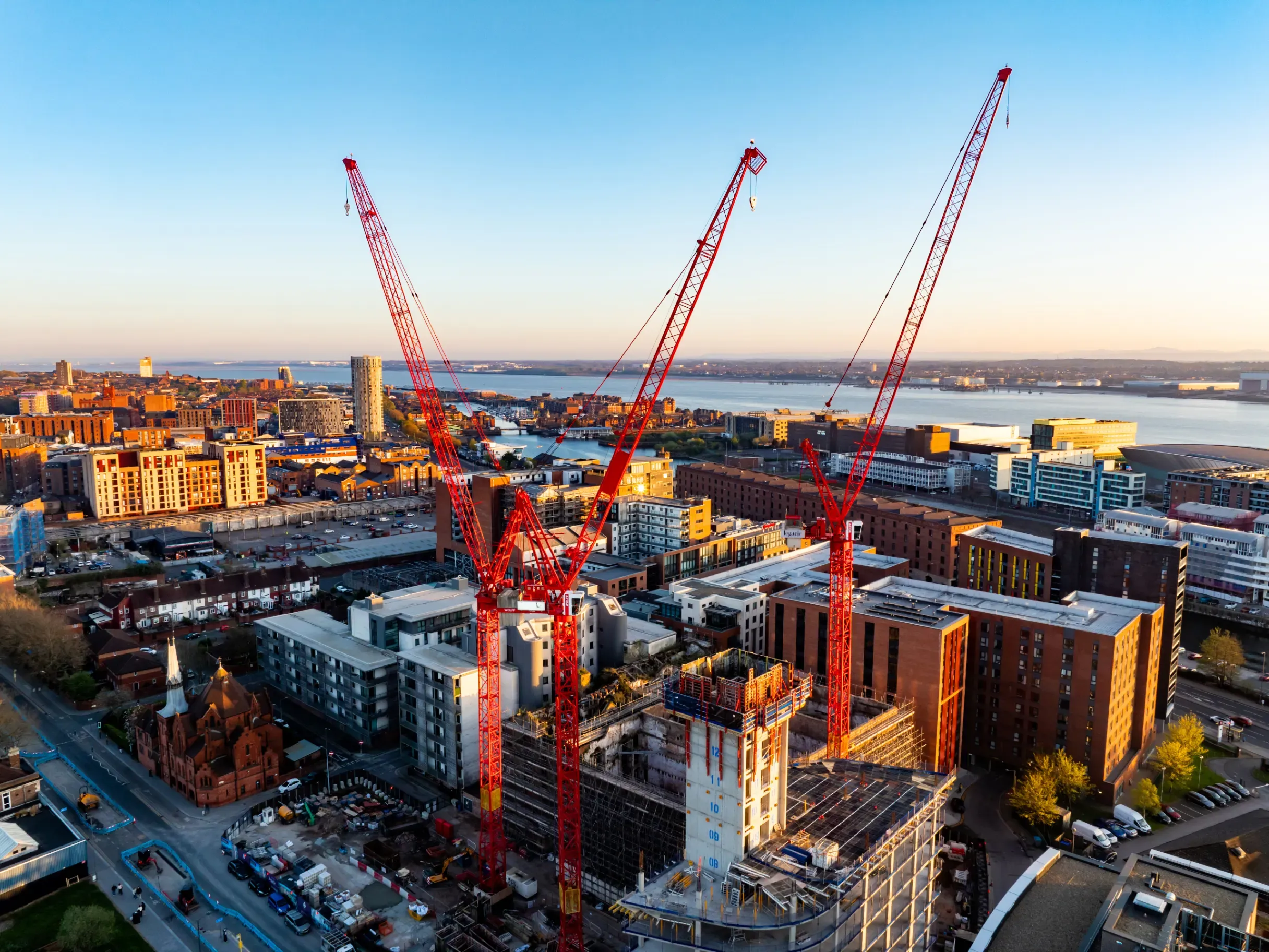 Construction cranes towering over an urban development site, highlighting large-scale building activity. 