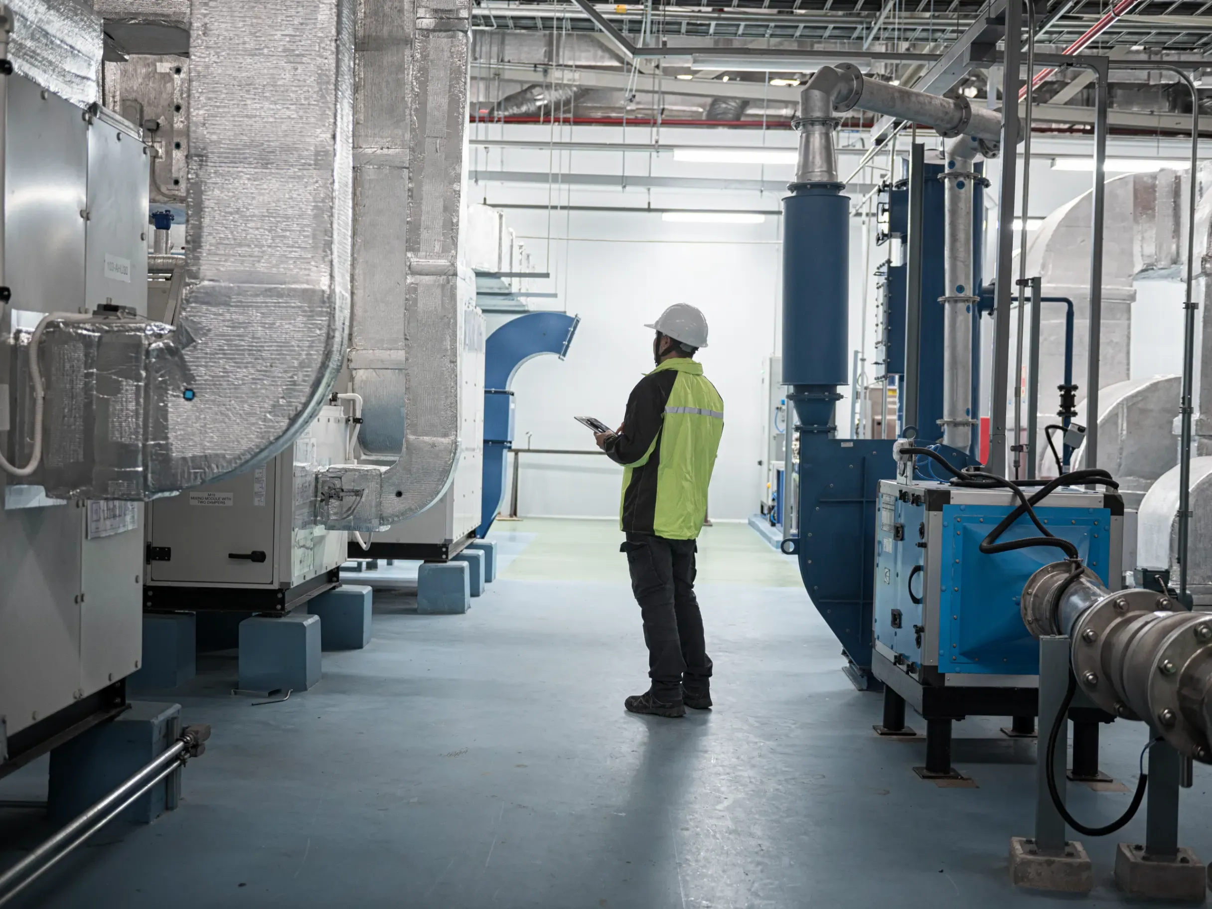 Engineer inspecting a modern industrial facility, reviewing equipment and operational infrastructure. 