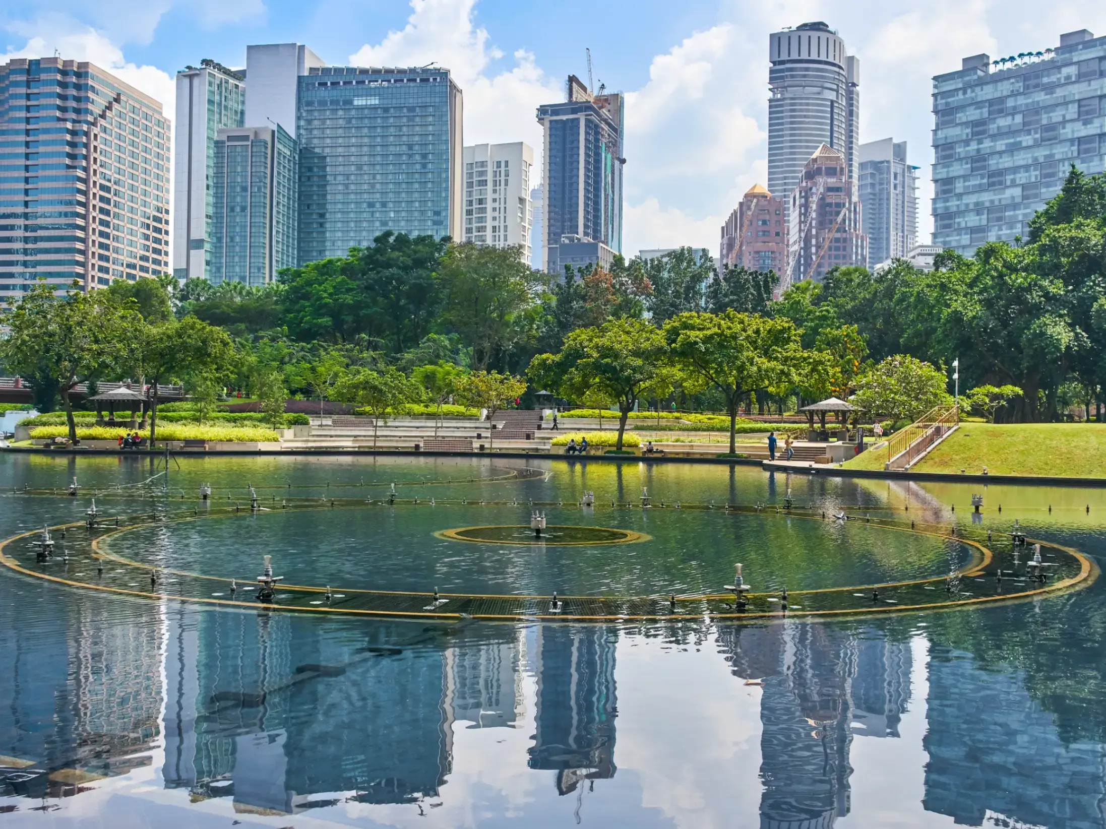 KLCC Park in Kuala Lumpur, Malaysia, with landscaped green space and views of the surrounding city skyline. 