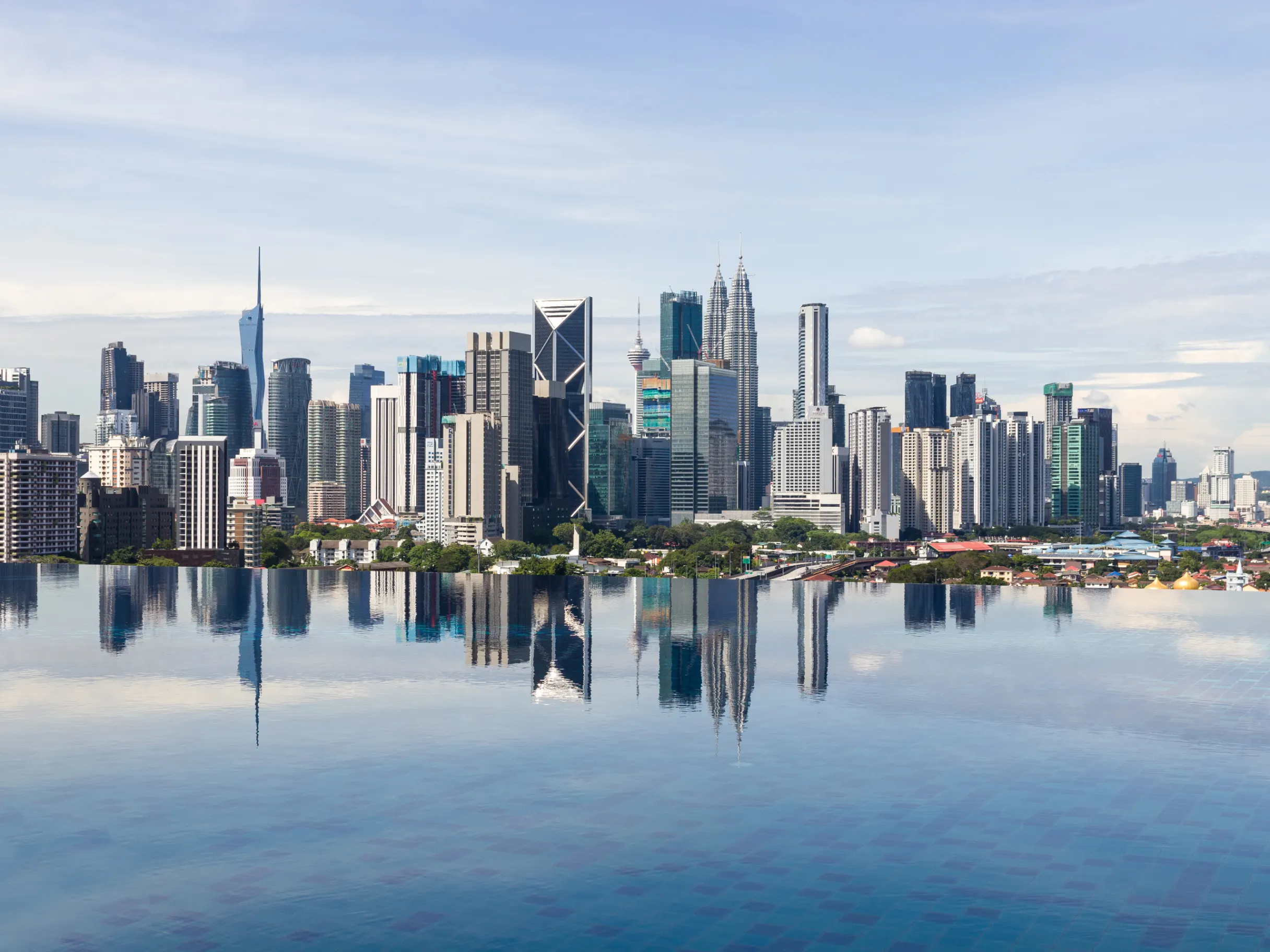 Kuala Lumpur cityscape viewed from the water, featuring a skyline of modern buildings.