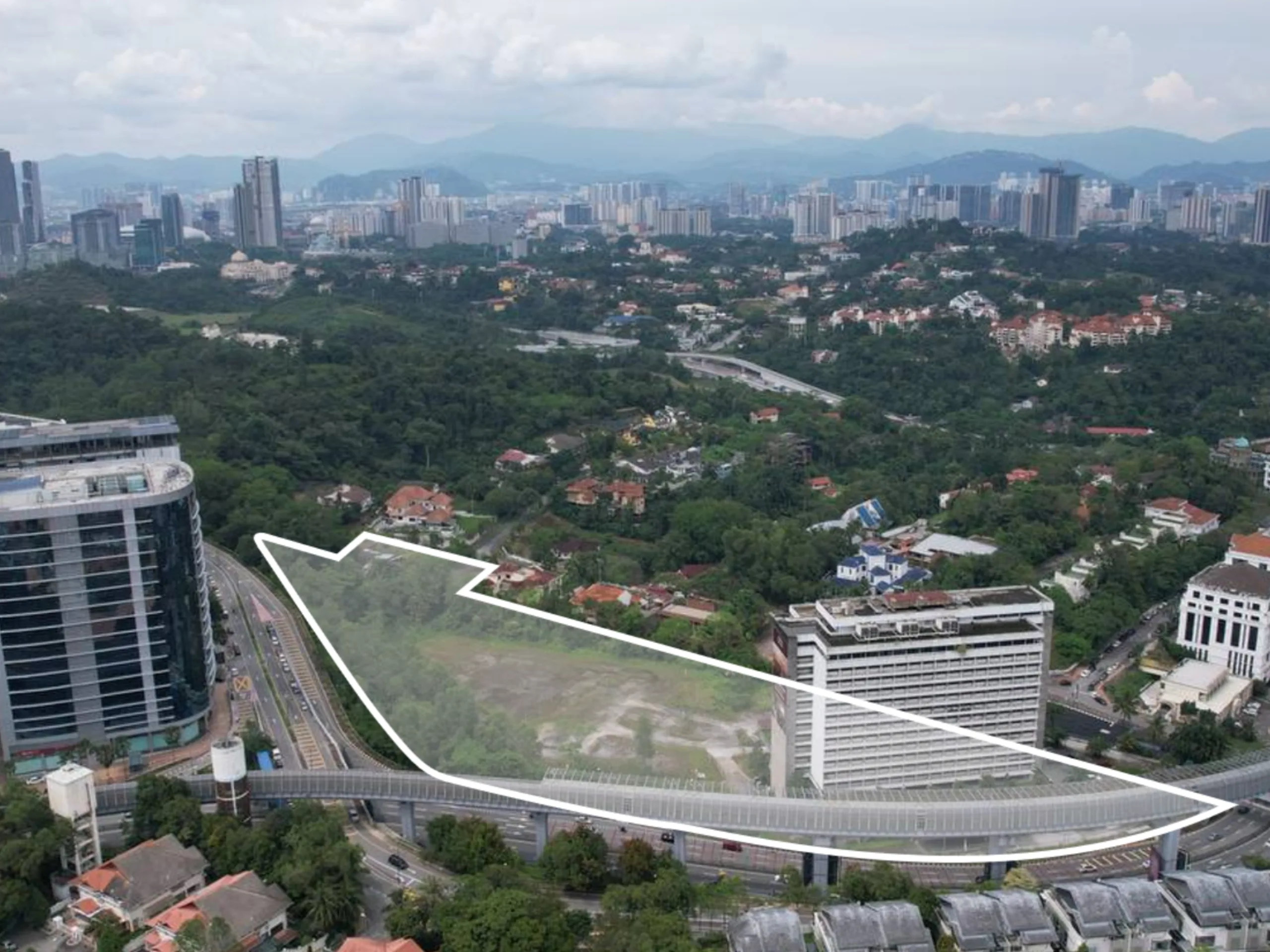 Overhead view of a site marked for development, showing surrounding buildings, roads, and land designated for future use.