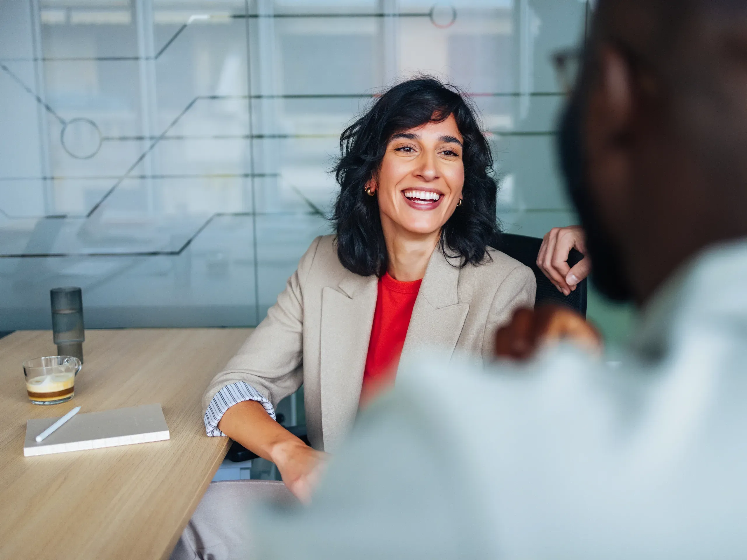Smiling woman participating in a business meeting, engaged in discussion with colleagues in a professional setting. 