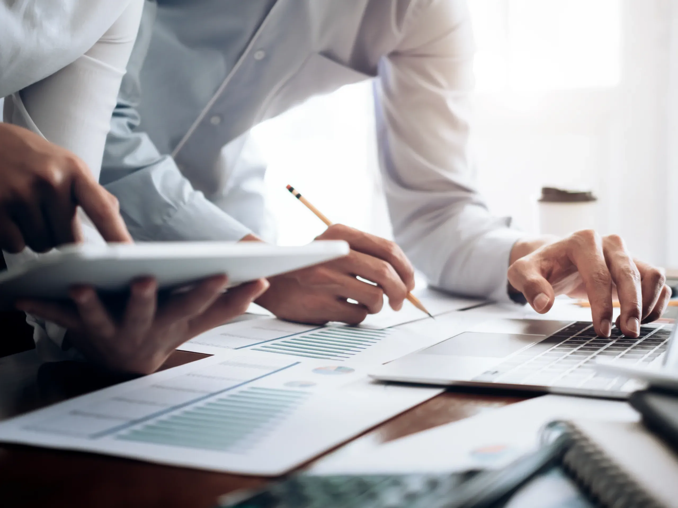 Two people working together at a desk, collaborating on tasks in a professional environment. 