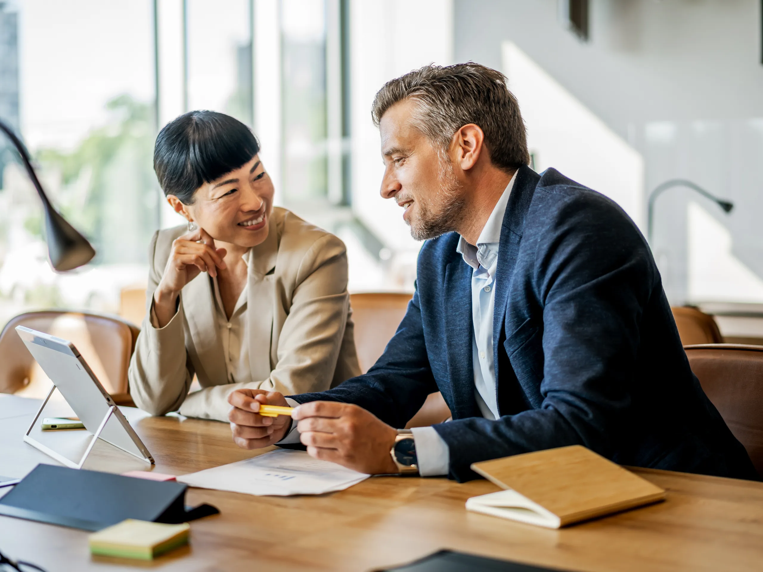Two work colleagues in a business meeting, collaborating in a professional office environment.
