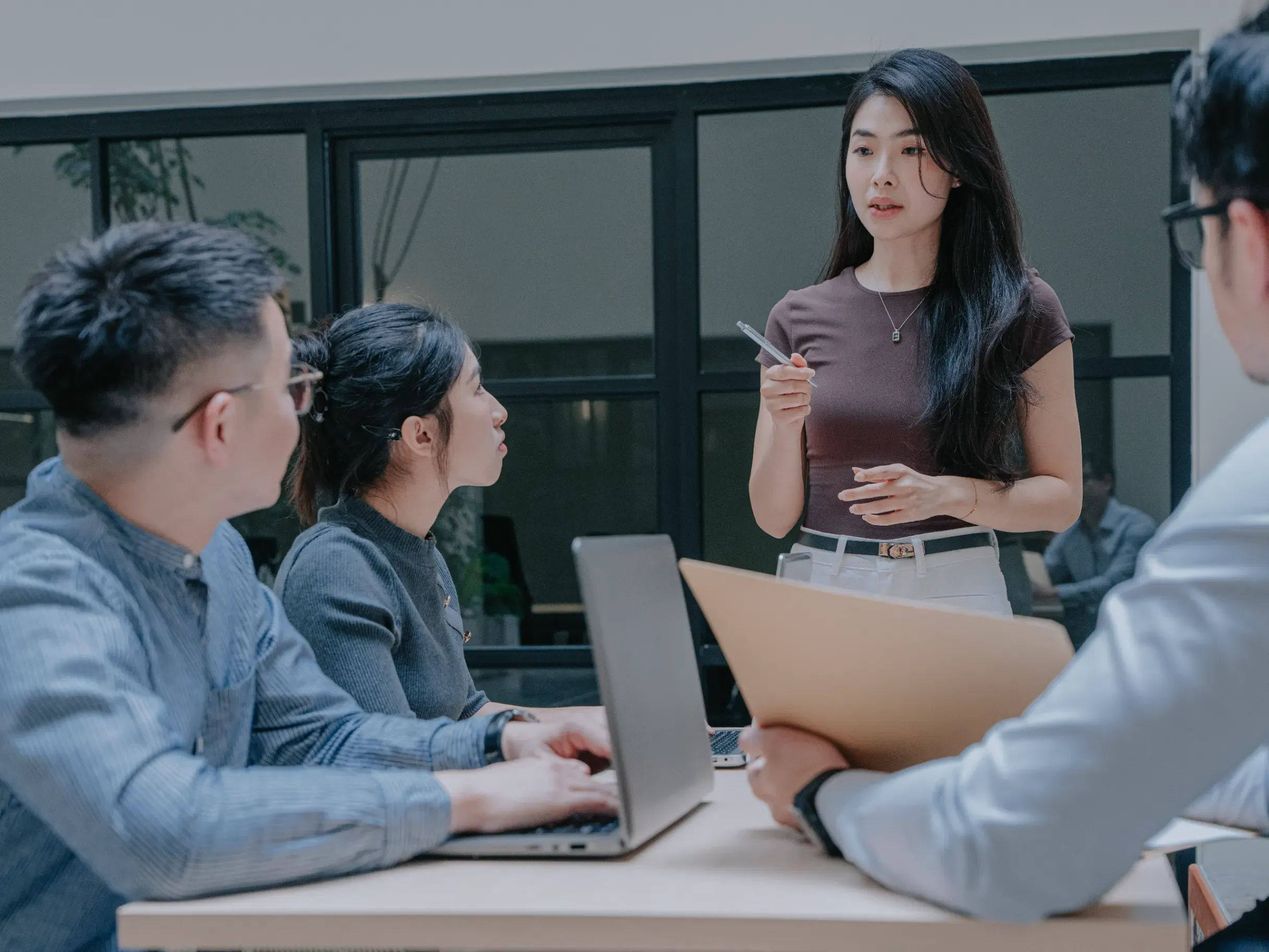 Asian businesswoman leading a discussion during an office meeting with coworkers, presenting ideas and encouraging collaboration. 