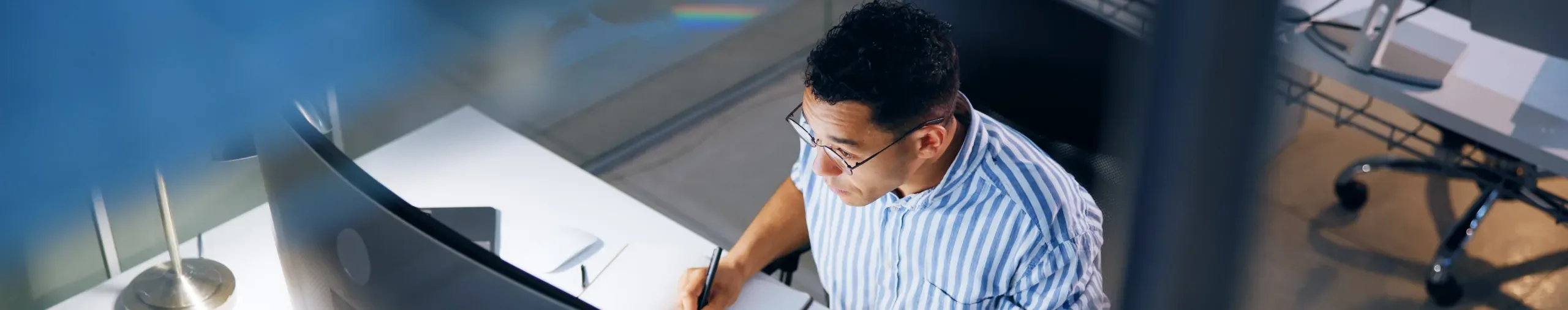 Businessman working at a desk in front of a computer monitor - banner