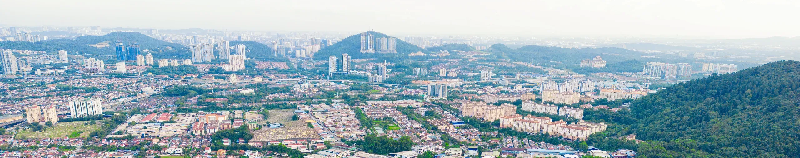 Drone view of a suburban neighbourhood showing residential streets, homes, green spaces, and surrounding infrastructure. 