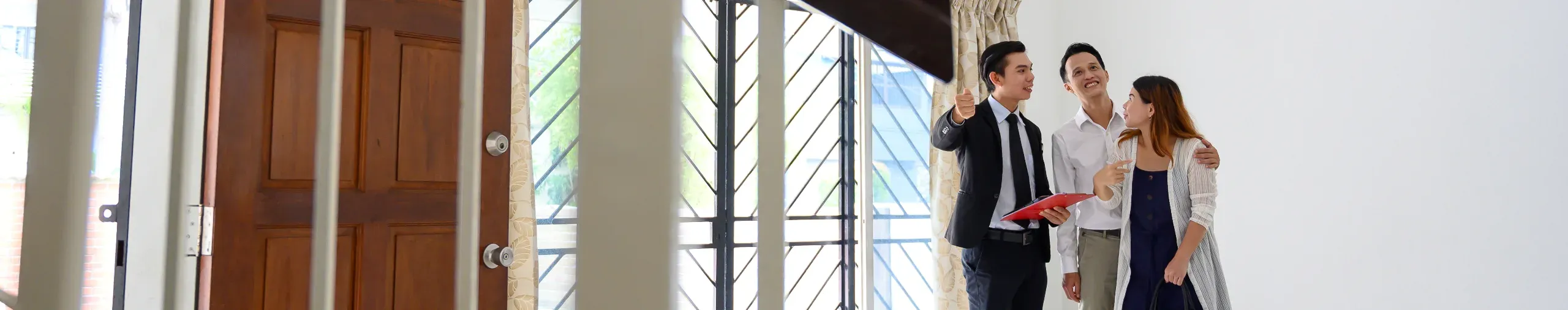 Real estate agent showing a property to an Asian couple, discussing features during a viewing. 