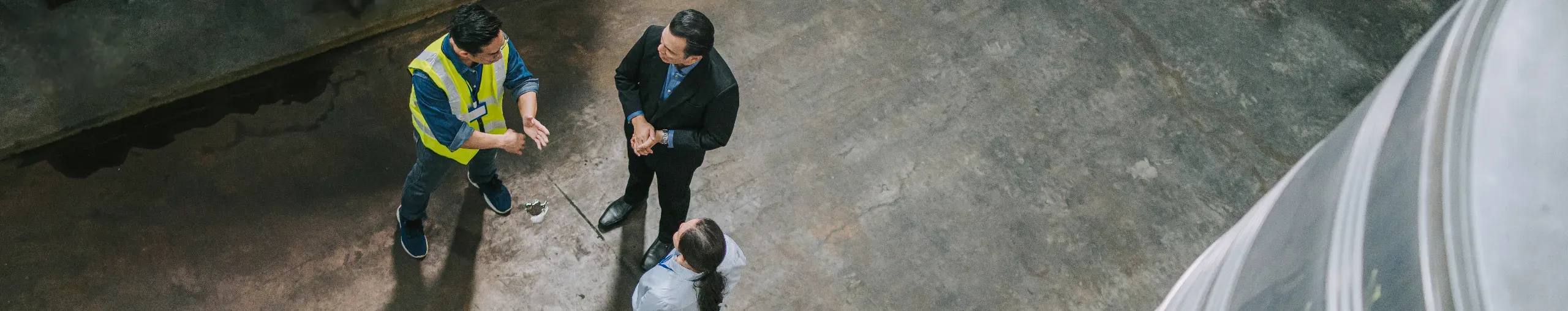 Three professionals discussing logistics operations in a warehouse. 